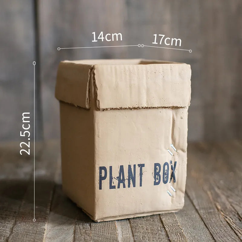Cement flower pot with brown paper box design showing perforated drainage base