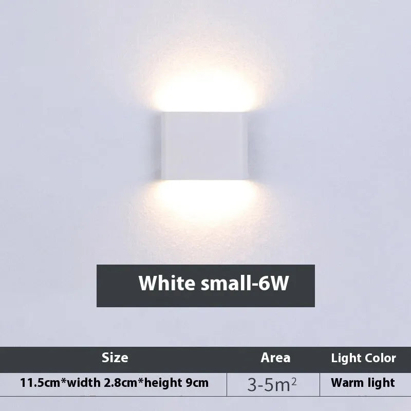 Rectangular LED outdoor wall lamp in black finish with warm light on a brick courtyard wall
