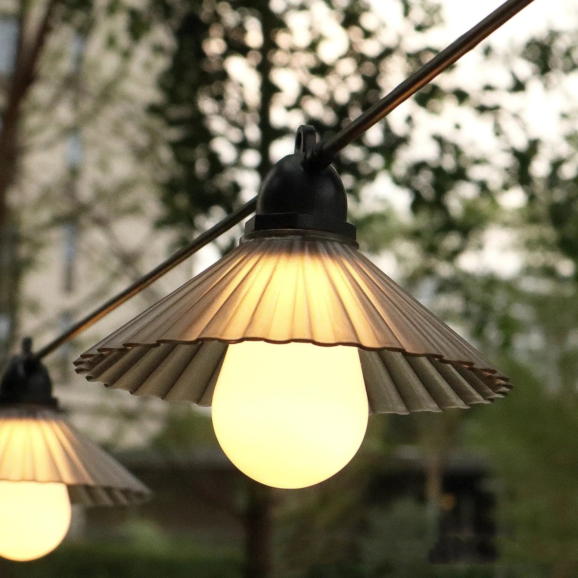 Outdoor LED string lights with flower-shaped bulbs hanging in a garden setting.