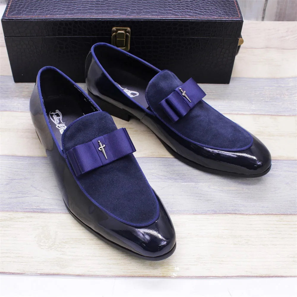 Men's black tassel loafers with matte and glossy patent leather uppers and a rubber sole, shown on a wooden surface.