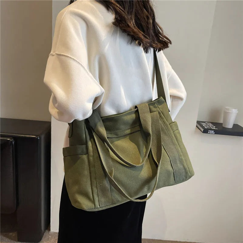 Large solid colour polyester canvas shoulder bag for women showing external pocket and strap.