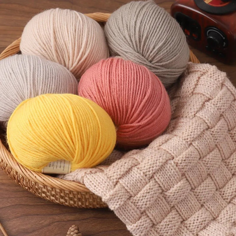 One roll of fine, twisted woolen hand-knitting yarn in a colour from the available palette, shown next to knitting needles.