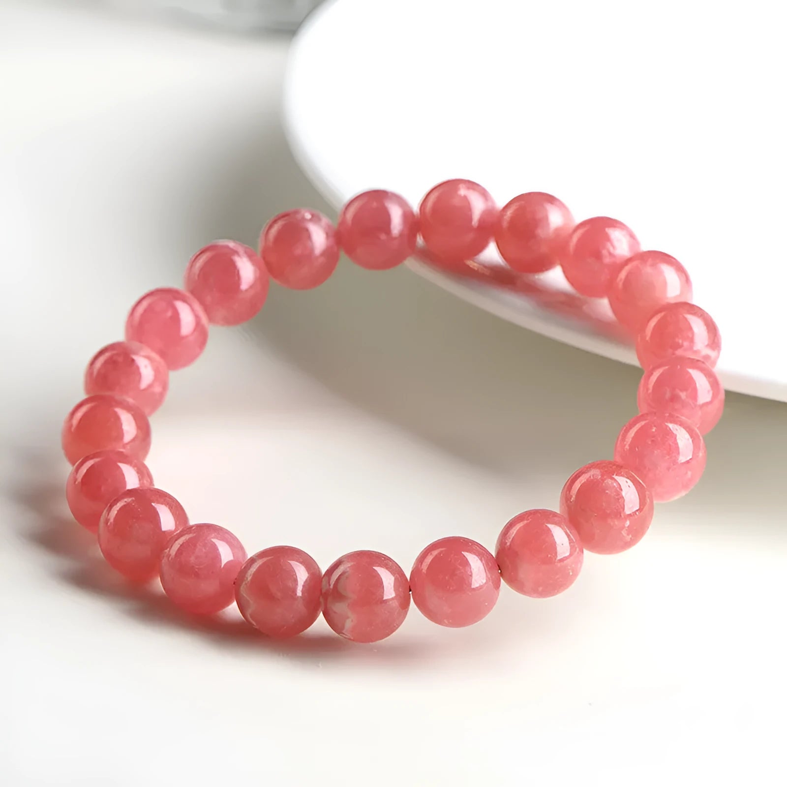 Women's geometric rhodochrosite crystal bracelet with a longevity lock clasp on a wrist.