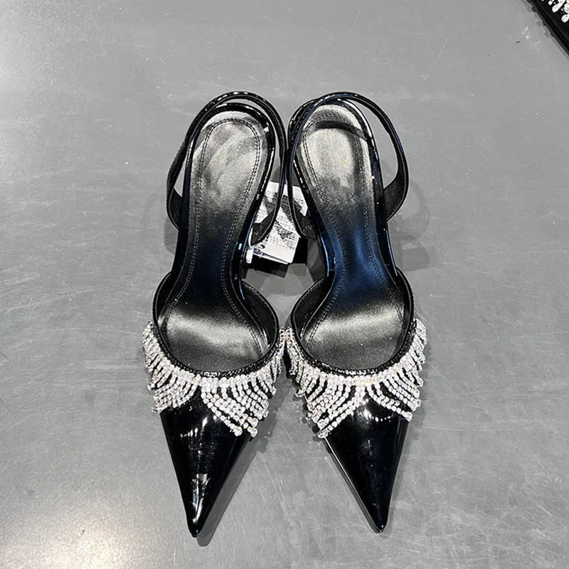 Black women's slingback high heel sandals with rhinestone and tassel decoration on a pointed toe.