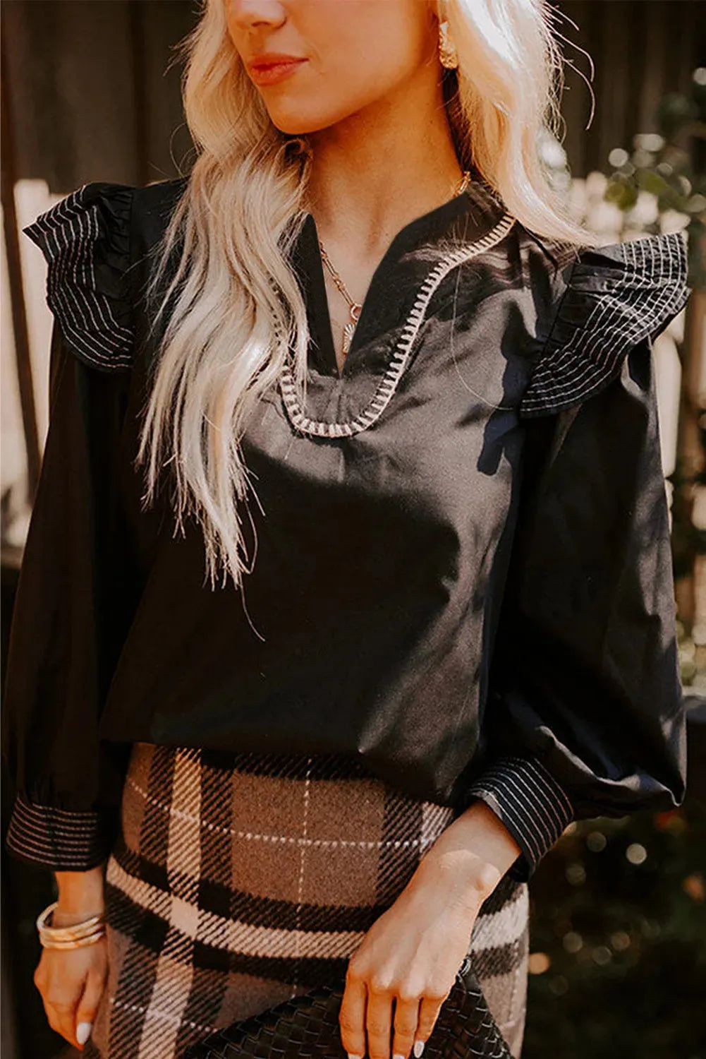 Black V-neck long sleeve blouse with ruffle trim and contrast colour stitching.