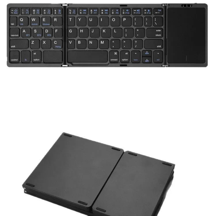Three folding wireless Bluetooth keyboard with touch pad in black, open on a table next to a mobile phone