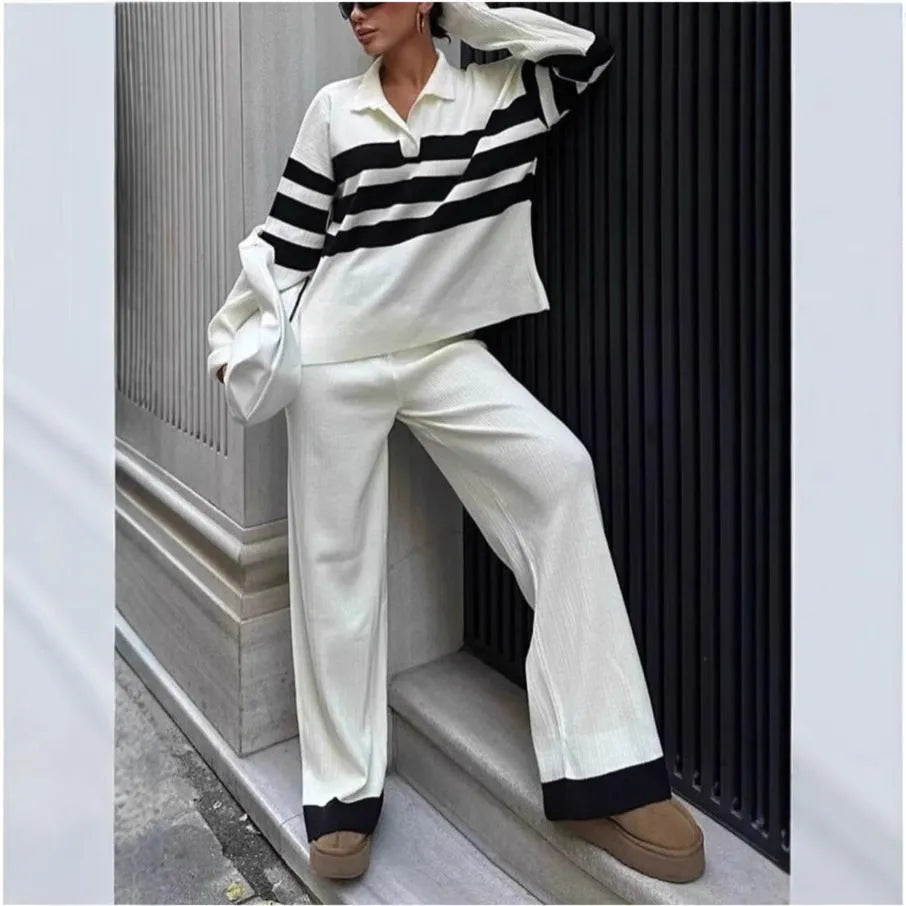 Women's black and white striped knitted two-piece set with polo collar top and full-length trousers.