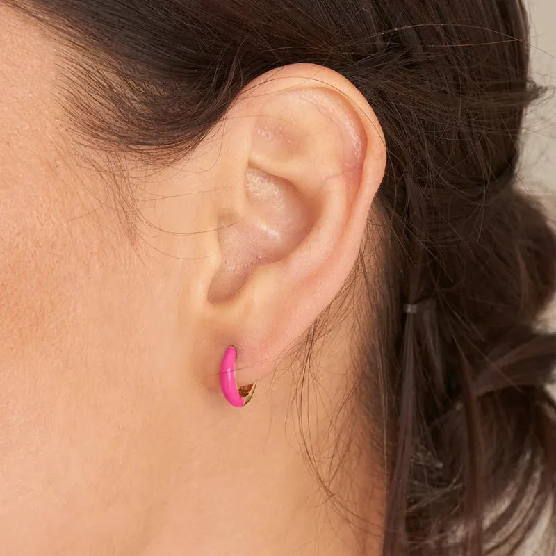 A pair of glossy light green epoxy oval earrings with a U-shaped curve and silver-coloured post on a grey background.