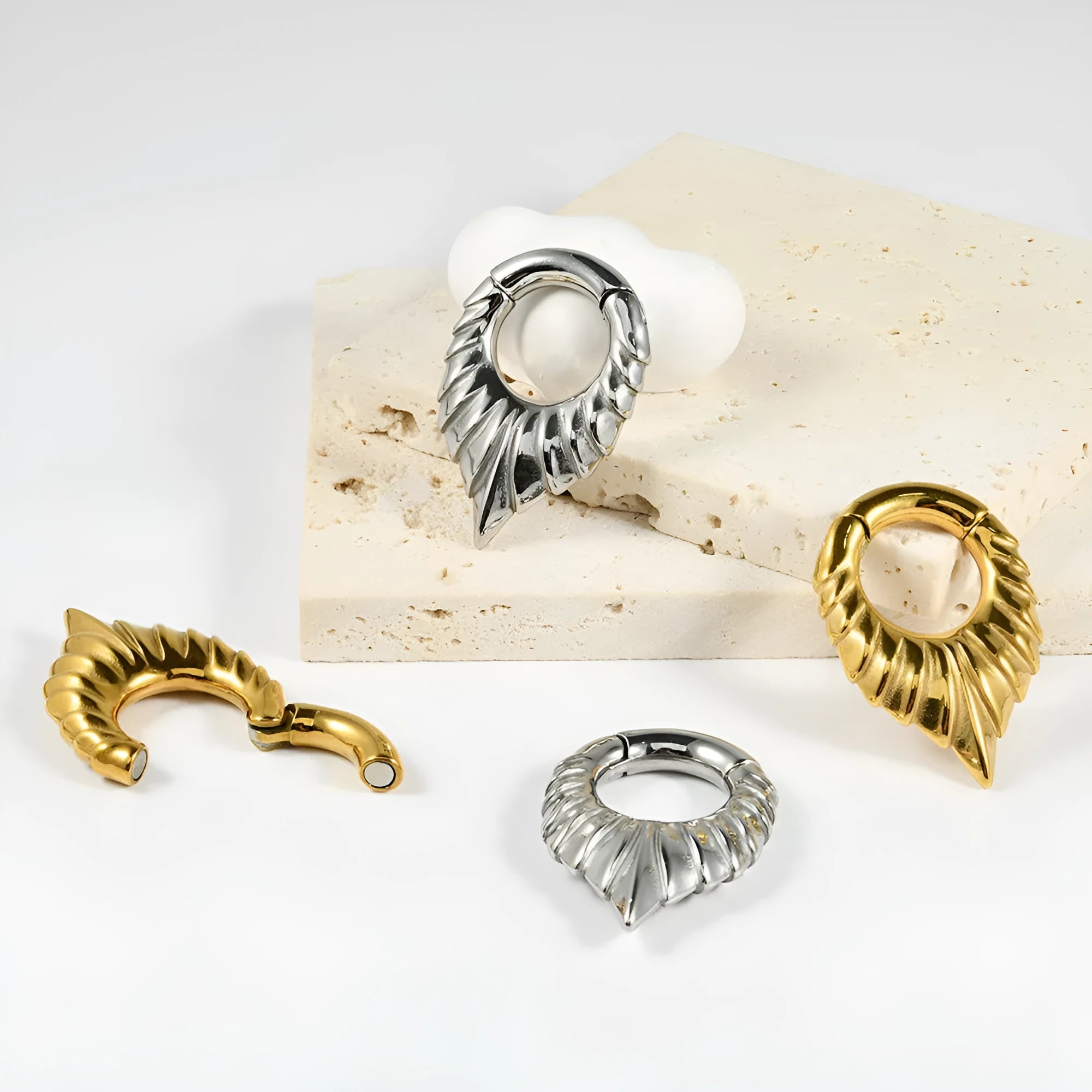 Close-up of a stainless steel drop-shaped ear extender with totem patterns, hanging vertically.