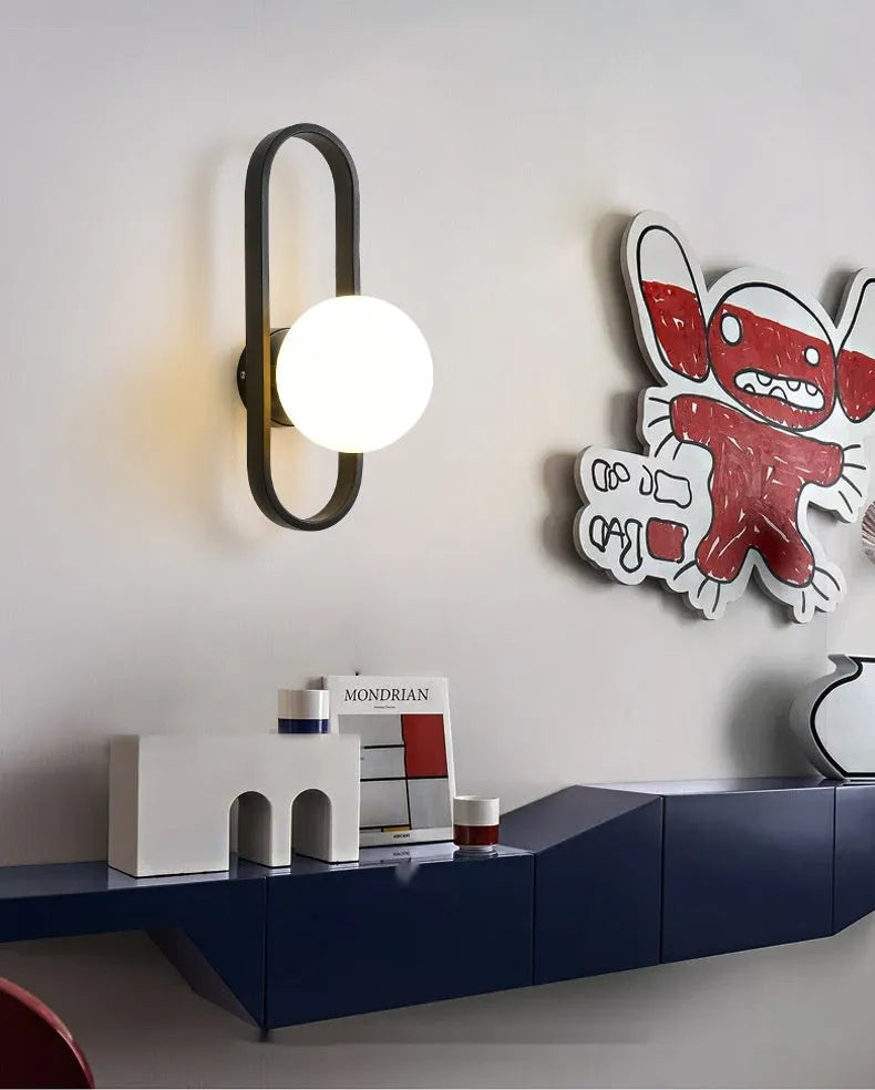 Minimalist wall-mounted lamp with glass shade and iron body in black or gold finish, showing 12W tri-colour LED light.