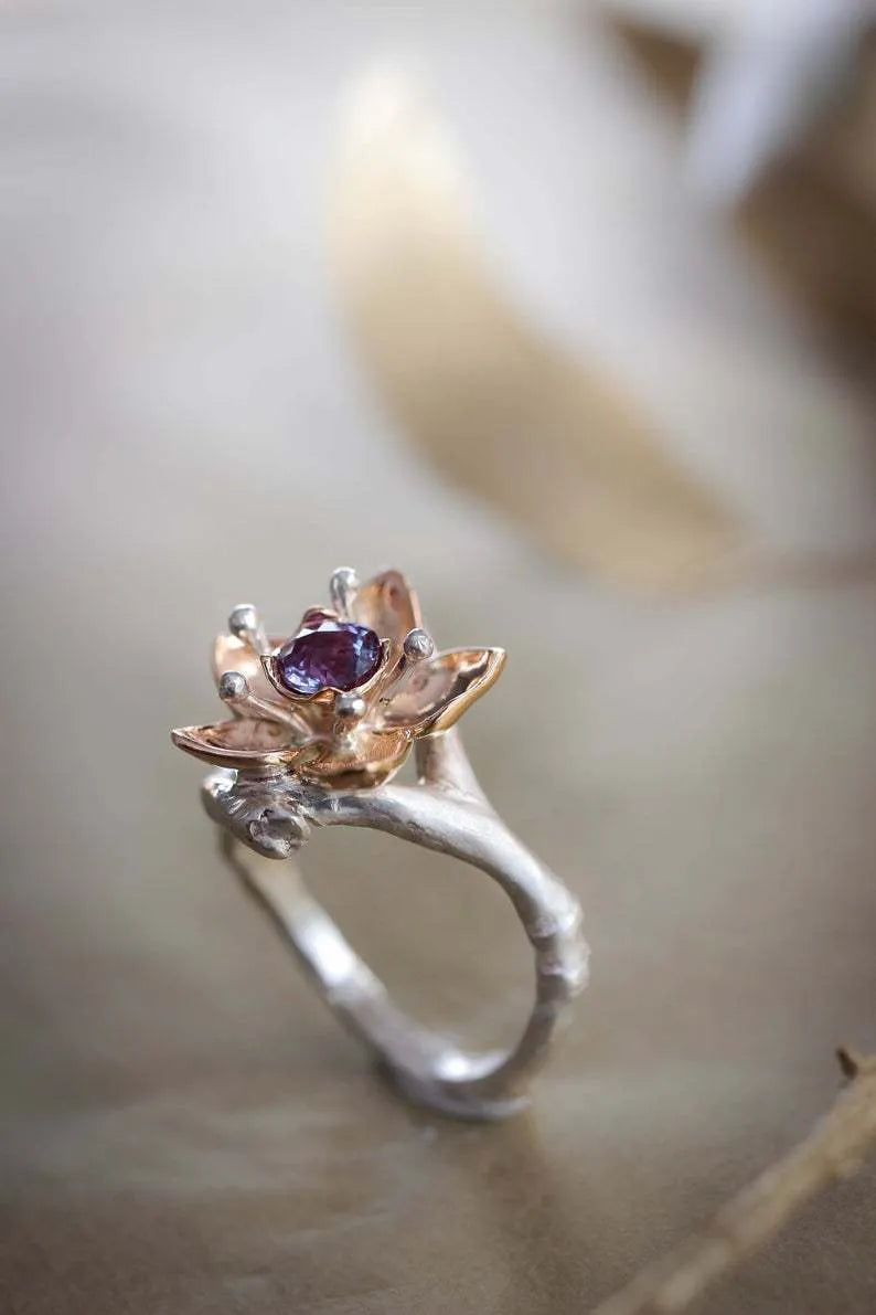 Geometric silver two-tone women's ring with open floral detail on a plain background.