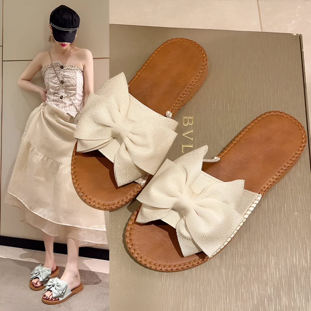 Women's beige suede slip-on sandals with a bow detail and soft rubber sole