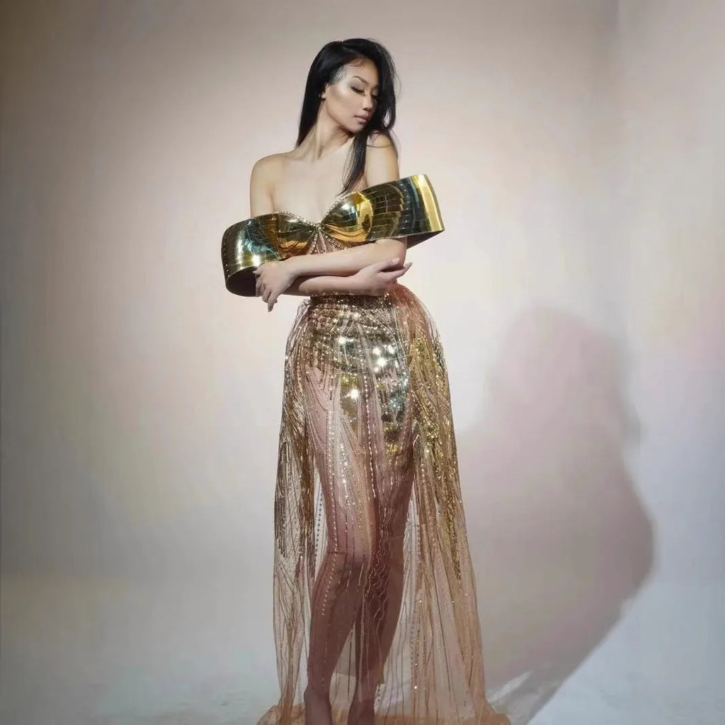 Gold strapless sequin evening dress with a long tulle skirt and thigh split on a mannequin.