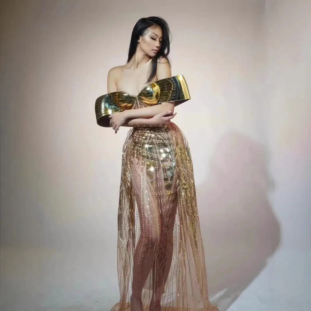 Gold strapless sequin evening dress with a long tulle skirt and thigh split on a mannequin.