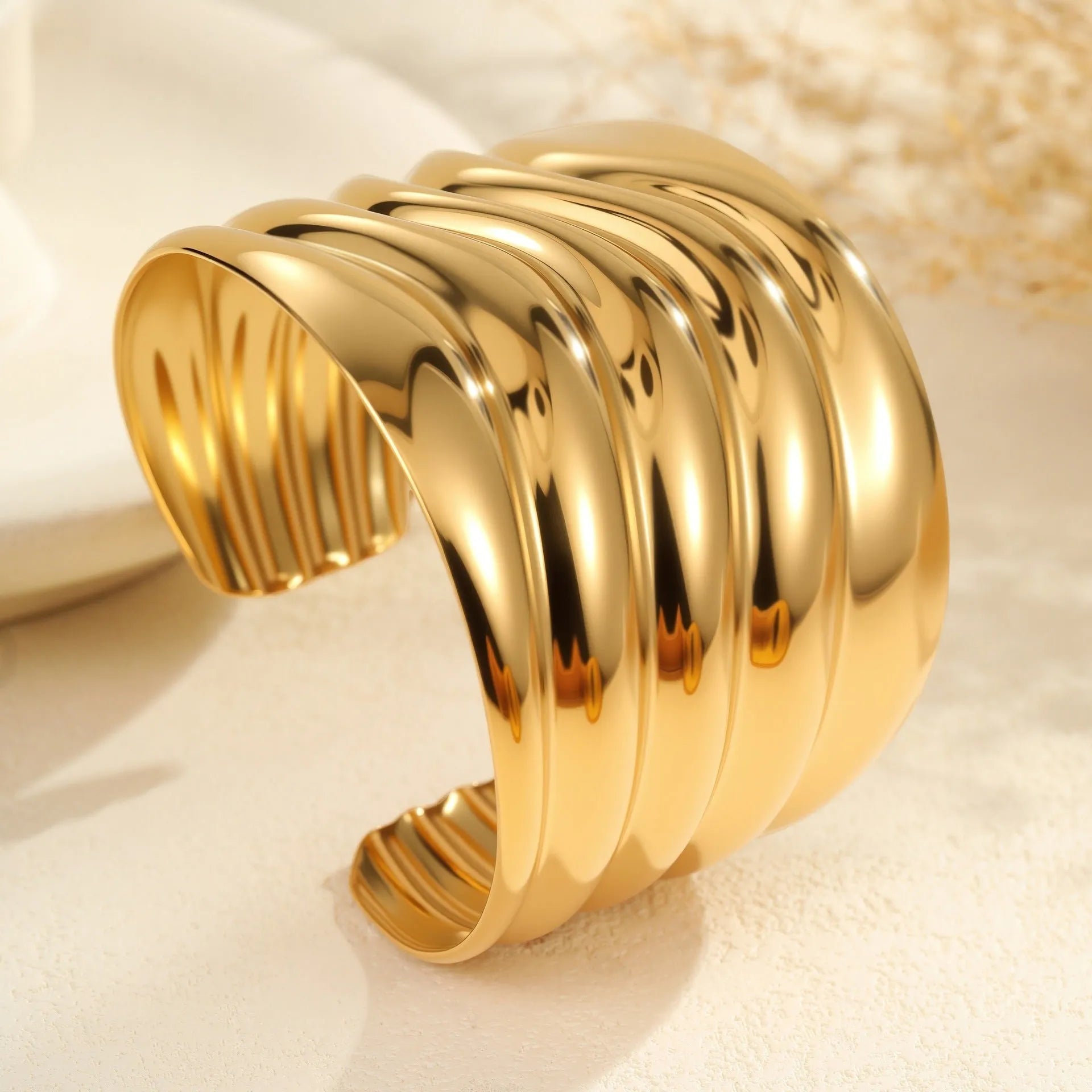 Women's wide stainless steel bracelet with 18K gold plating in a wave and geometric design.