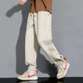 Men's black loose-fit ankle-tied sports trousers with high waist and drawstring closure on mannequin