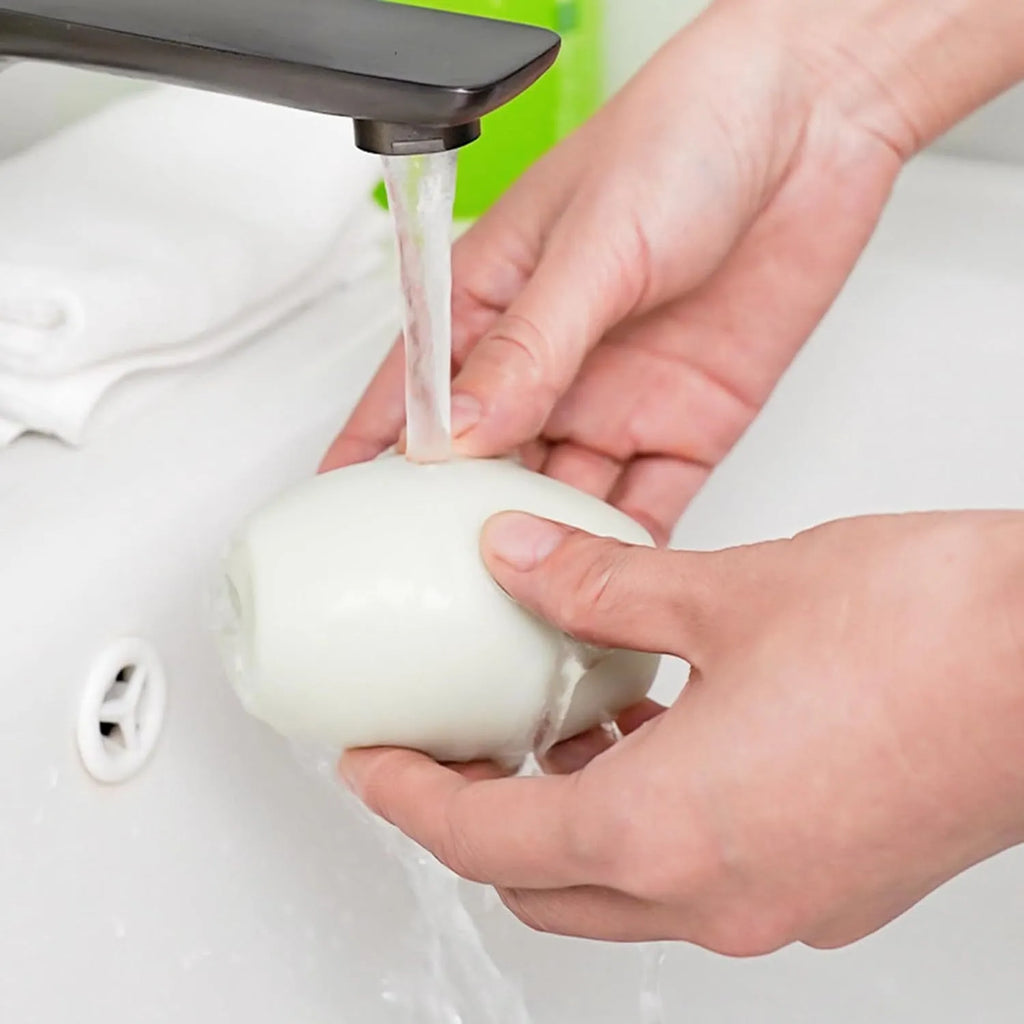 Green and white reusable gel lint roller ball for removing pet hair and lint from clothes.