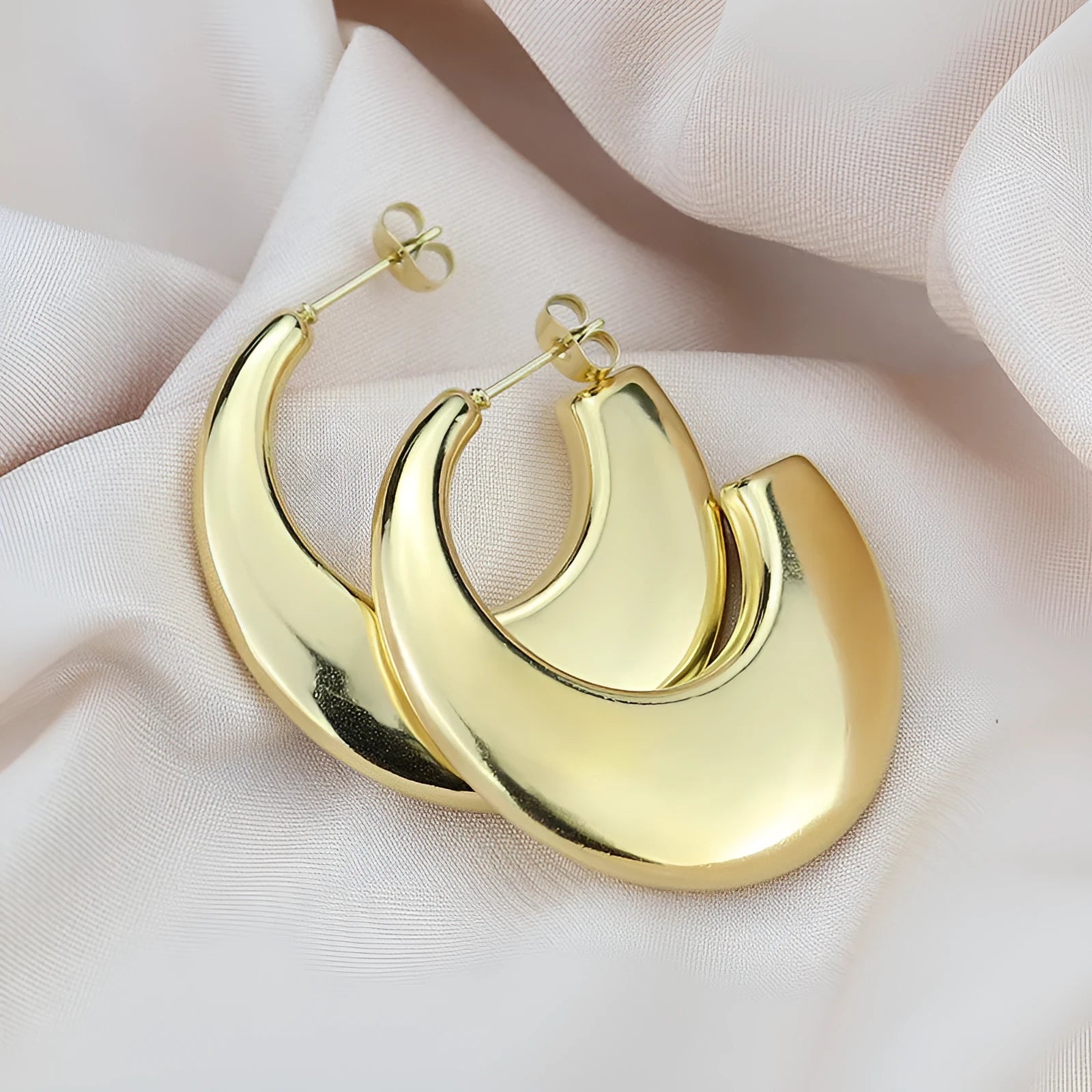 Two pairs of geometric thread stud earrings in gold and steel colour on a flat surface