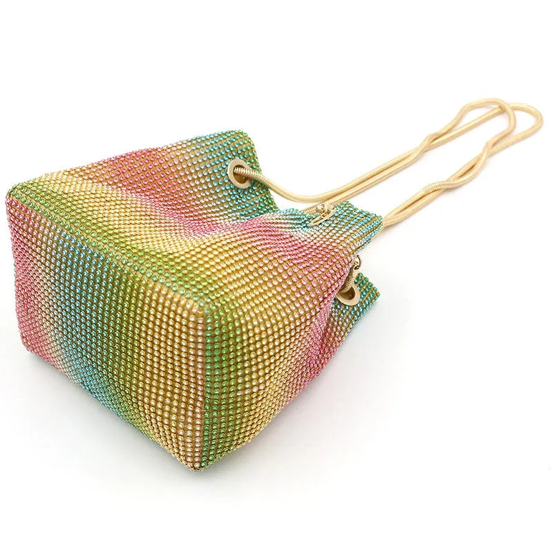 Soft rainbow rhinestone bucket bag with adjustable metal chain strap on a 28cm circular base.