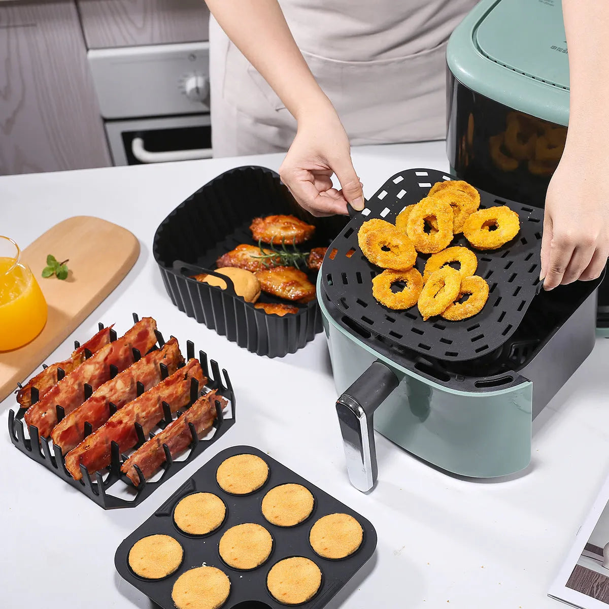 Black silicone square baking tray set for air fryer, 4 pieces on a light background