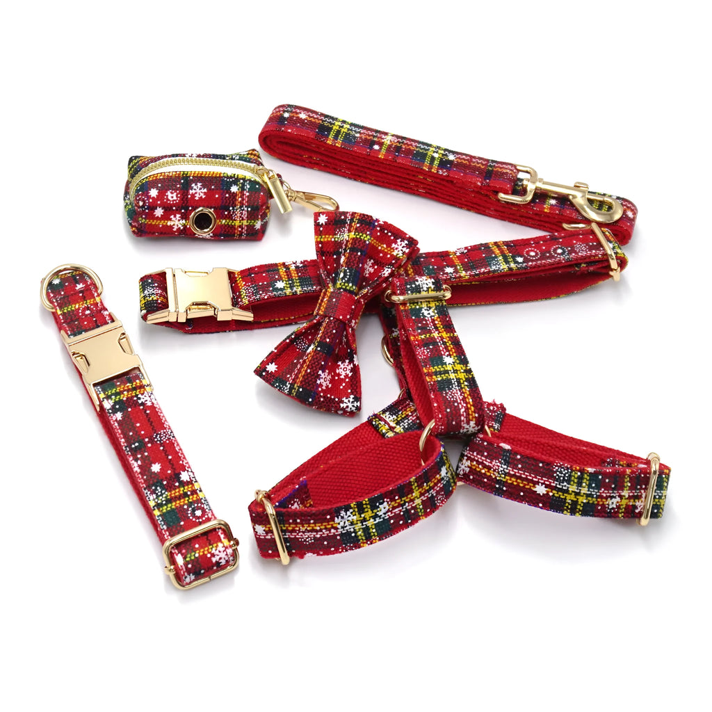 Red Christmas pet collar set with matching harness, leash, bow, and dog waste bag on cloth background