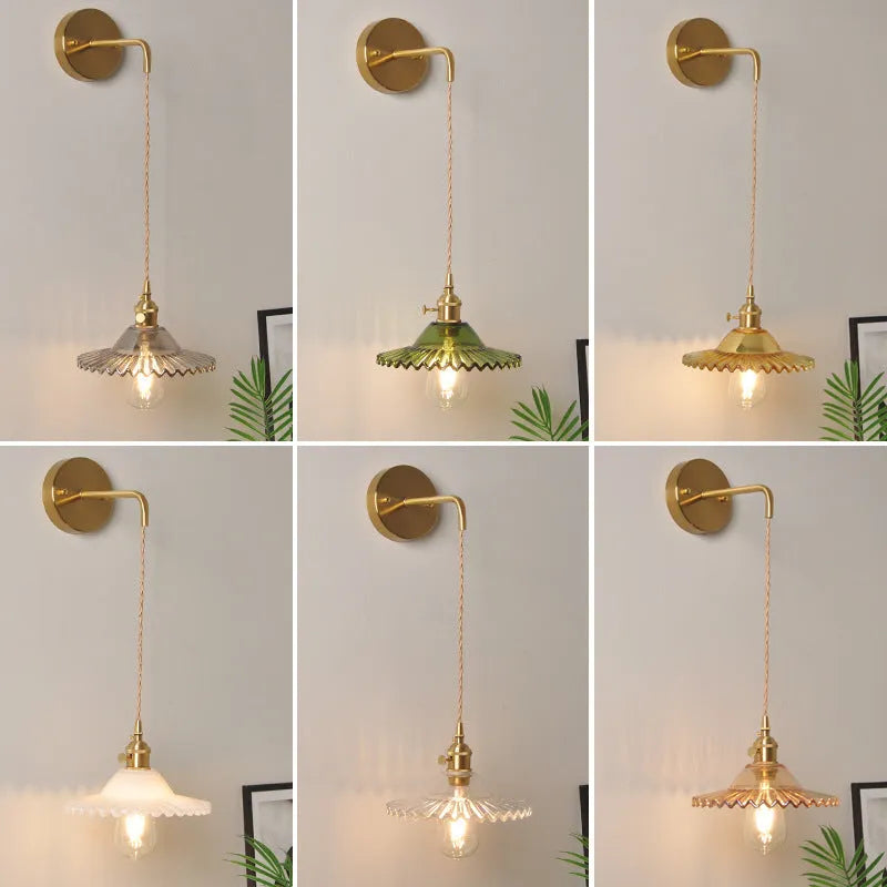 Retro brass lotus wall lamp with a smoky grey glass shade hanging on a 30cm wire beside a bed.
