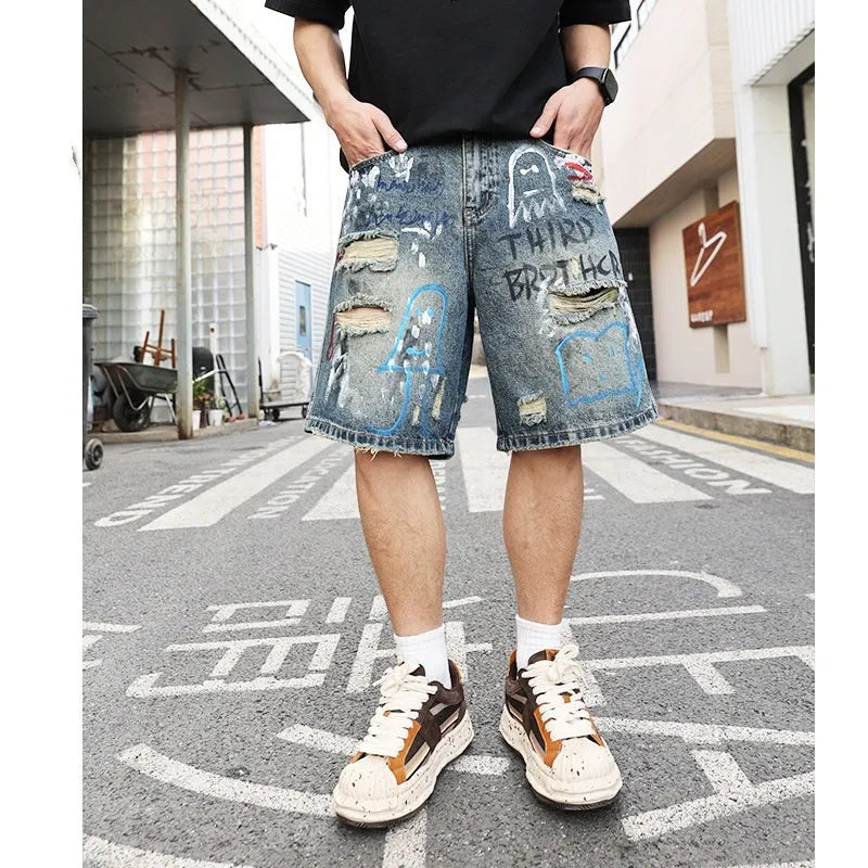 Blue denim shorts for men with ripped knees and graffiti design, featuring a straight leg and zipper fly.