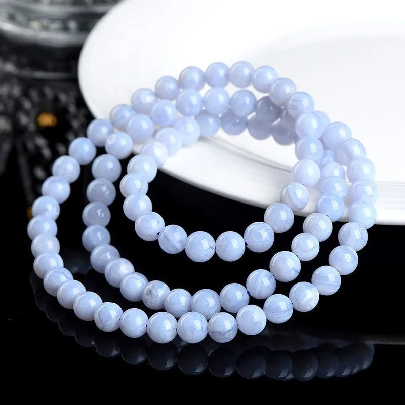 Close-up of a handmade blue agate bracelet with natural striped beads on a wrist.