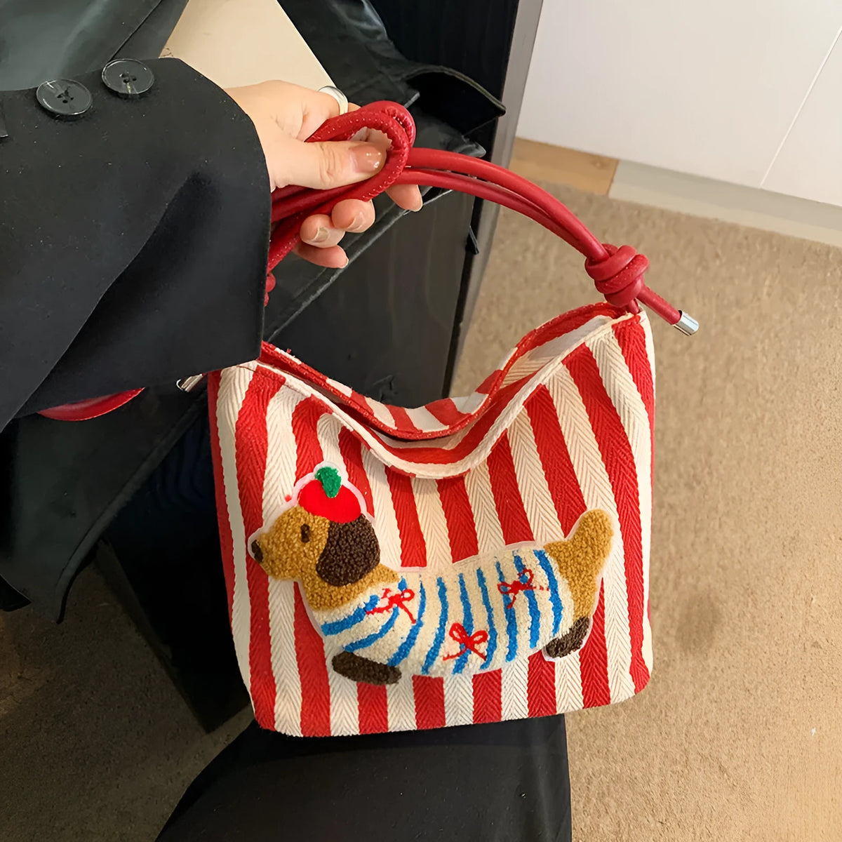 Cartoon sausage dog bucket bag in polyester with canvas lining, soft crossbody shape and single strap.