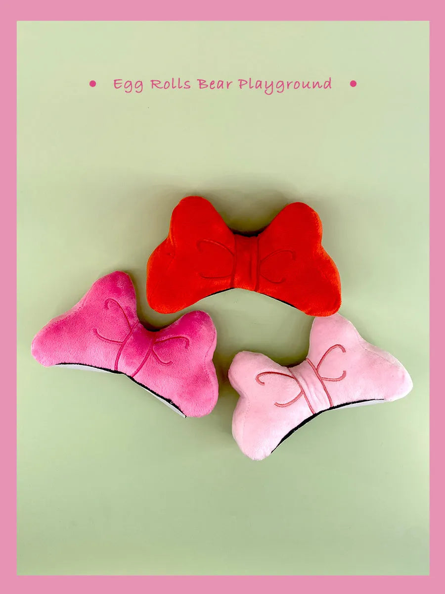 Soft red plush bow tie decoration for helmet customisation, shown against a helmet shell.