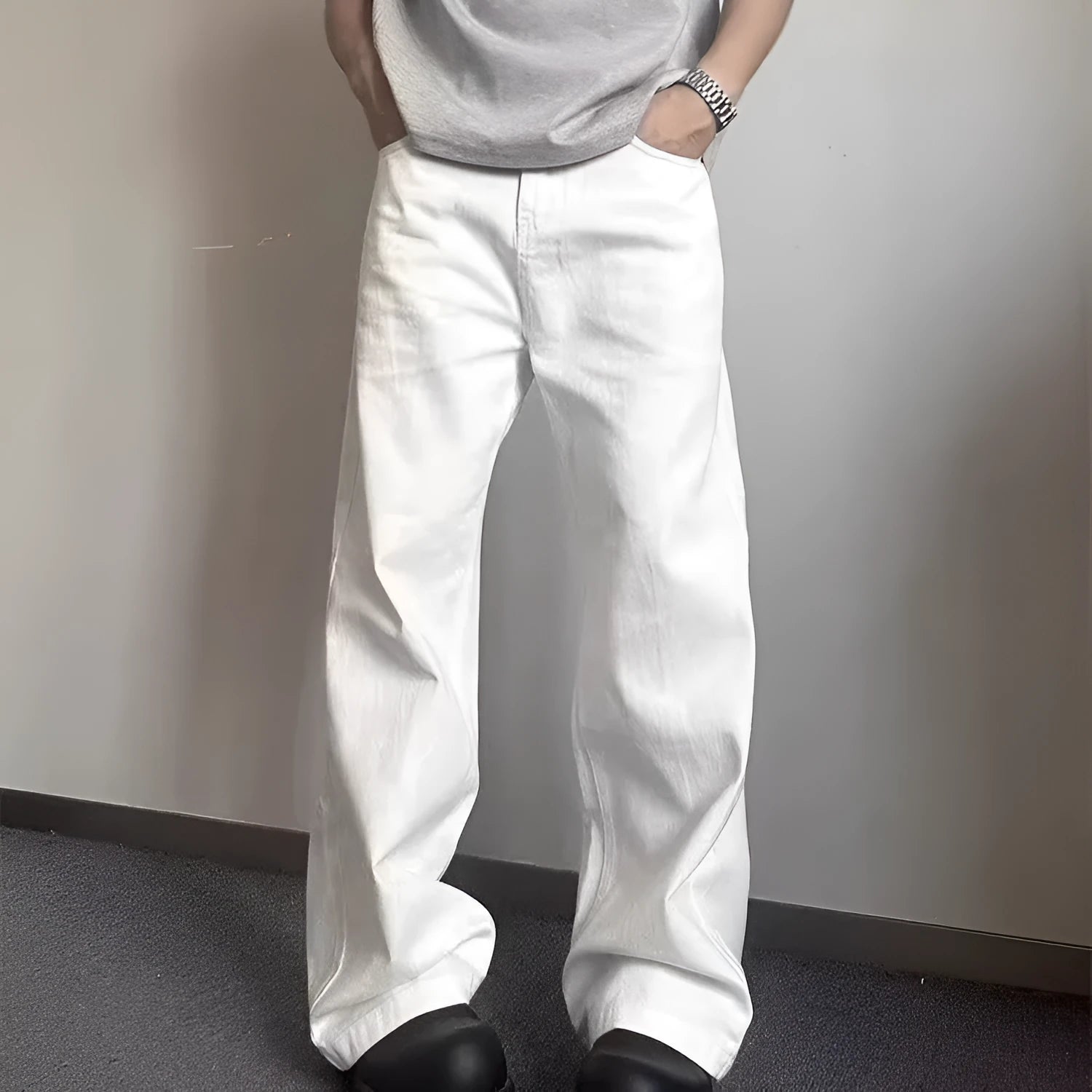 A man wearing white loose straight-leg cotton jeans with a mid-waist and zipper fly.