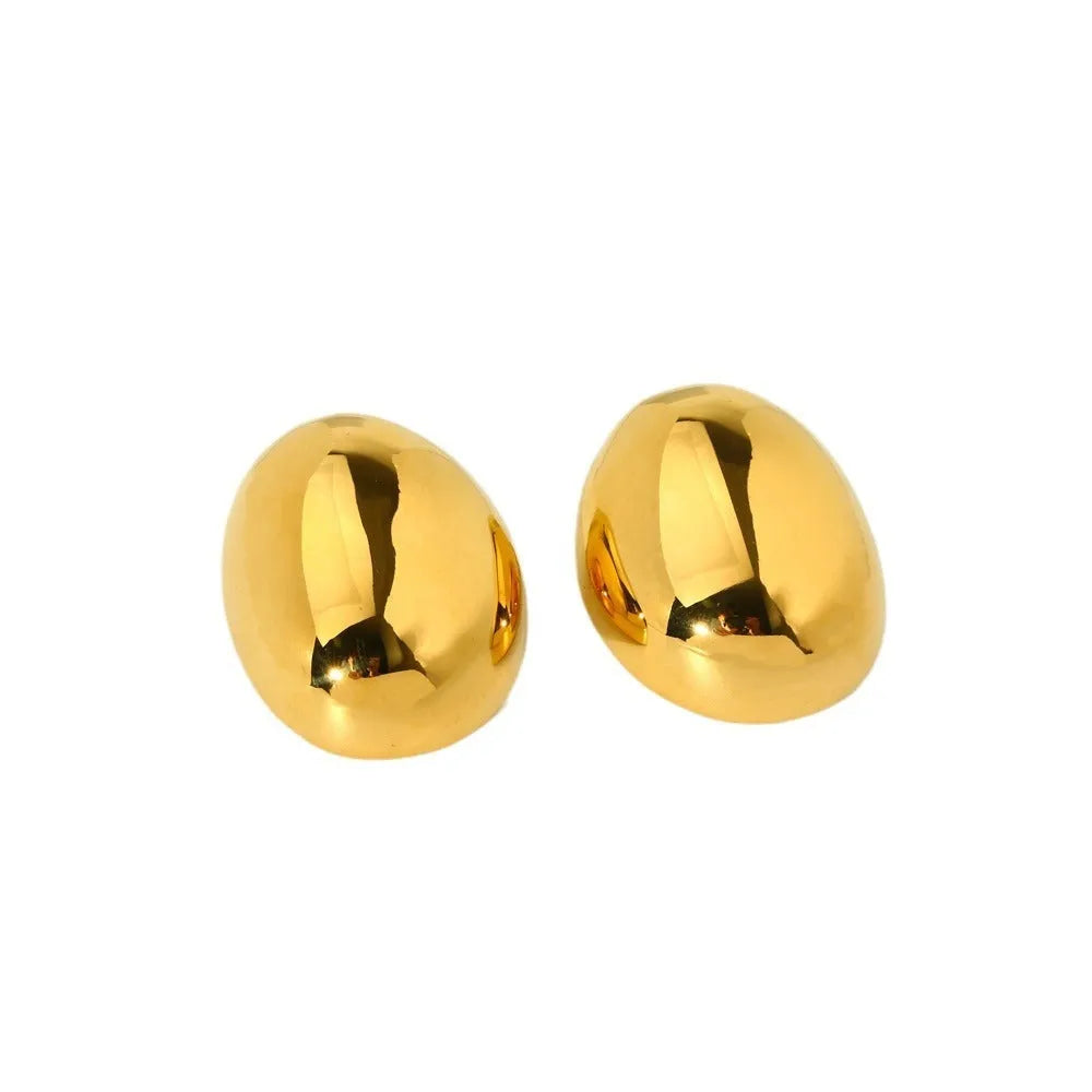 A pair of geometric gold-coloured ear studs with a glazed reflective surface and linear design details.