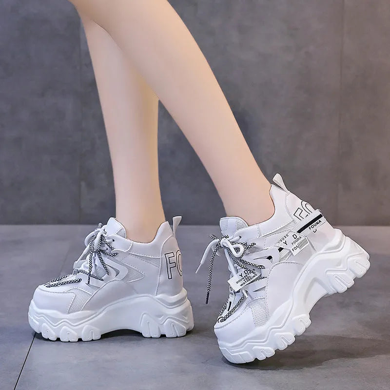 White women's low-top platform sports shoes with cross-strap detail on a rubber sole.