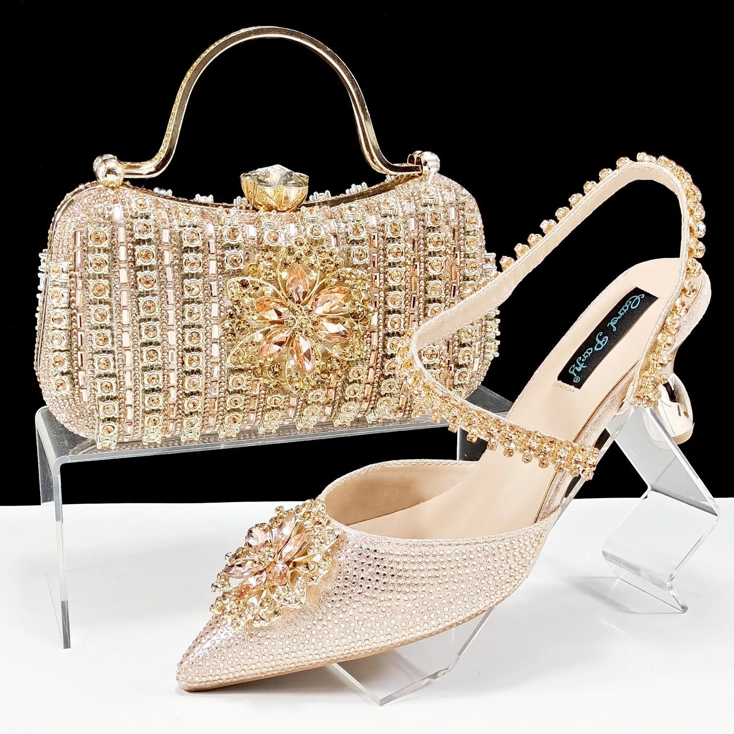 Women's black high heel shoe with floral rhinestone detail and matching hard clutch bag.