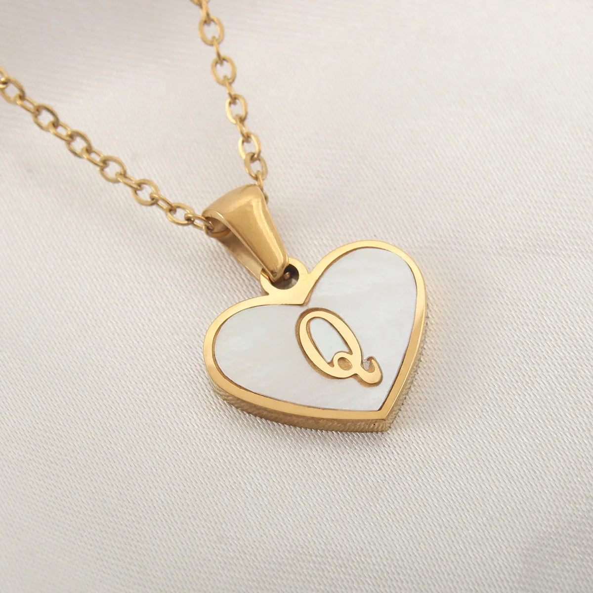 Gold-plated heart necklace with white shell pendant showing initial engraving on stainless steel chain