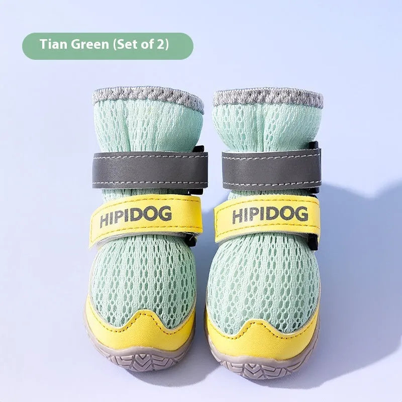 Pair of light blue cartoon-style dog shoes with adjustable strap, shown on a dog's paw.