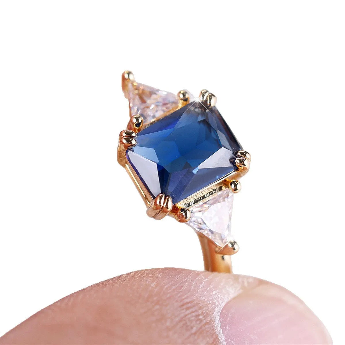 A gold sapphire blue rectangular copper ring for women on a jewellery display.