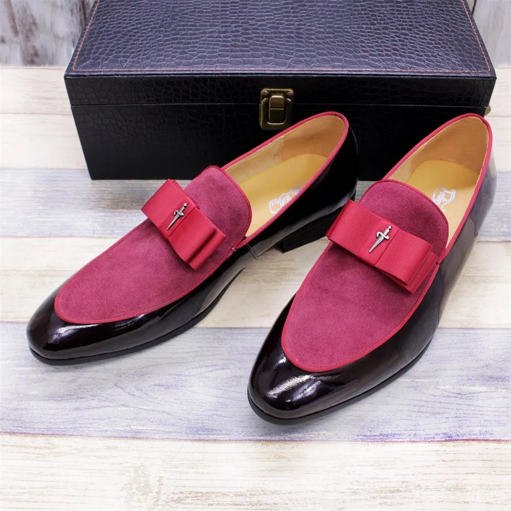 Men's black tassel loafers with matte and glossy patent leather uppers and a rubber sole, shown on a wooden surface.