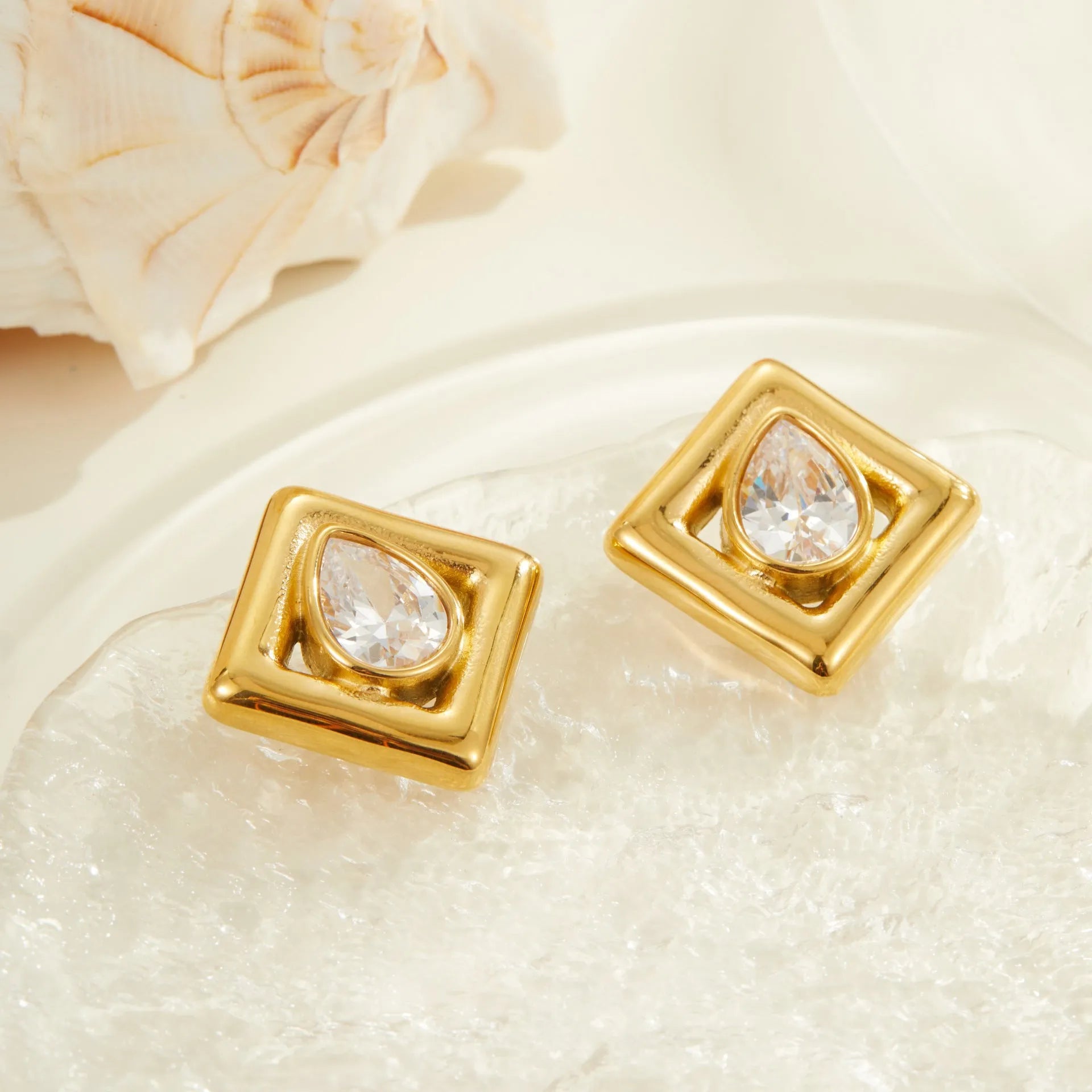 A pair of gold-coloured geometric stud earrings featuring an inlaid water drop zircon stone.