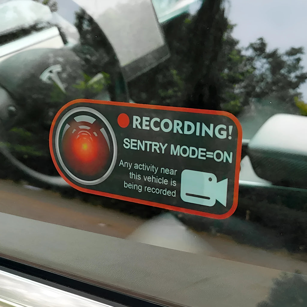 A pair of white rectangular Tesla Sentry Mode warning stickers with black text, measuring 11cm by 5cm.