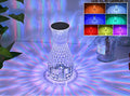 Vase-shaped crystal table lamp with LED lights and remote control on a bedside table