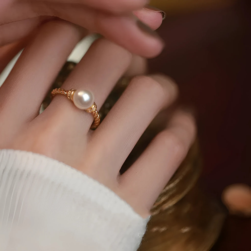 Adjustable antique-style copper ring with a round pearl inlaid in a geometric open frame on a twisted band.