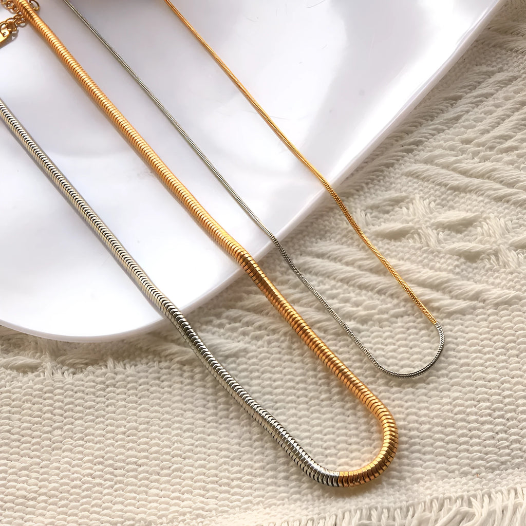Gold-coloured geometric snake bone chain necklace for women on a white background, showing adjustable extender.
