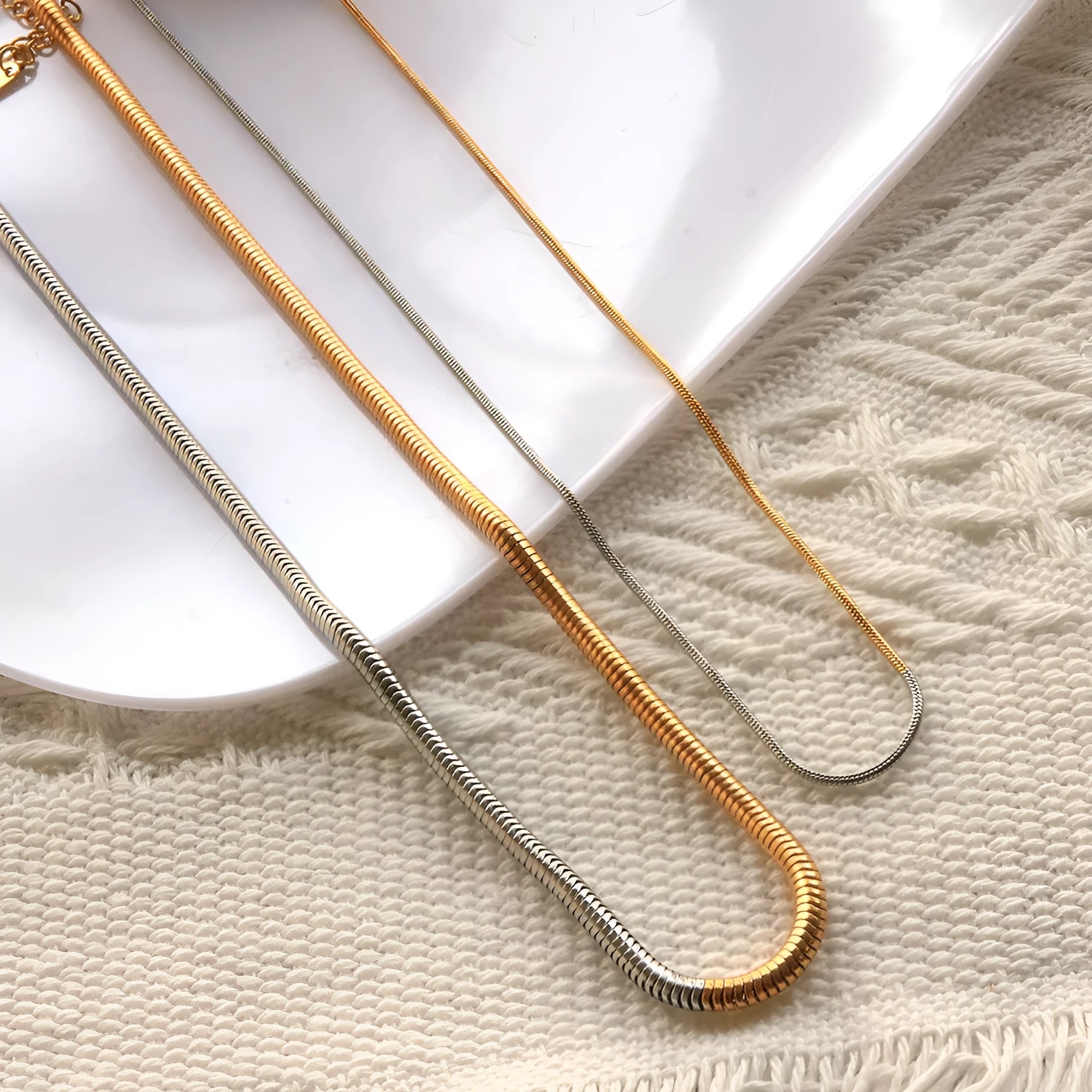 Gold-coloured geometric snake bone chain necklace for women on a white background, showing adjustable extender.