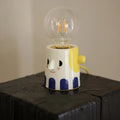 Handmade ceramic table lamp with white spherical shade on a wooden surface.
