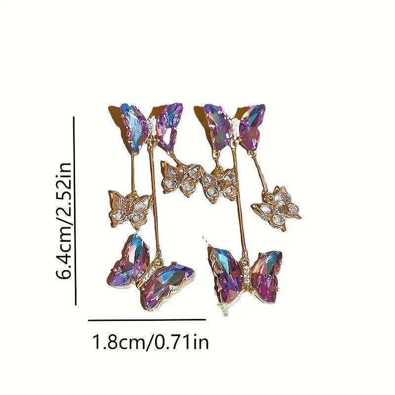 Long silver drop earrings with a blue-purple butterfly, crystal flowers, and a delicate tassel on a white background.