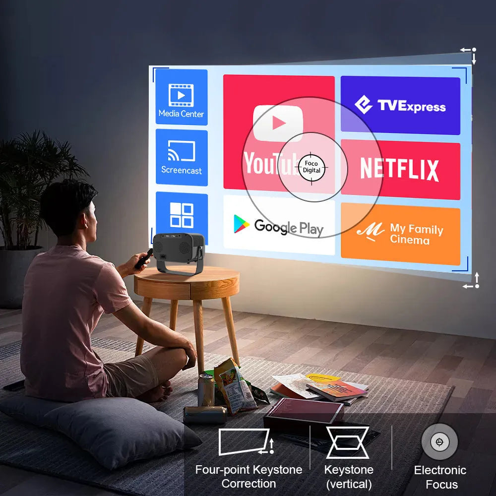 Black portable smart HD projector with remote control on a desk.