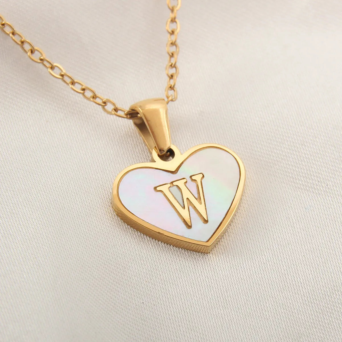 Gold-plated heart necklace with white shell pendant showing initial engraving on stainless steel chain