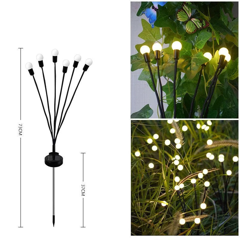 Solar-powered LED firefly garden stake light with stainless steel ground plug illuminated at dusk.