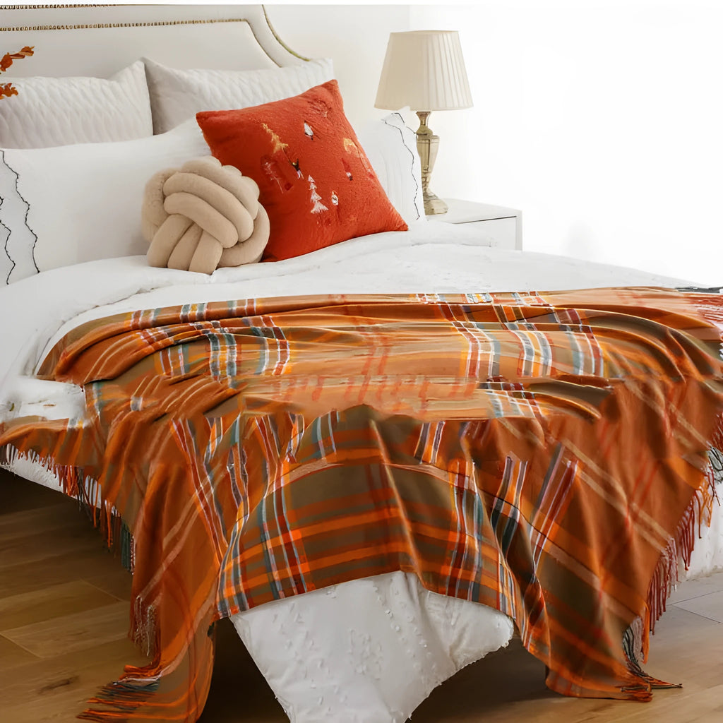 Acrylic chenille plaid throw blanket with tassel trim in gray and white geometric pattern on sofa